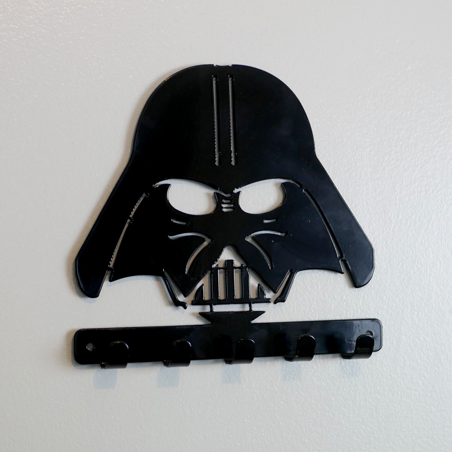 A black metal Star Wars Darth Vader hanging plaque with five small hooks along the bottom.
