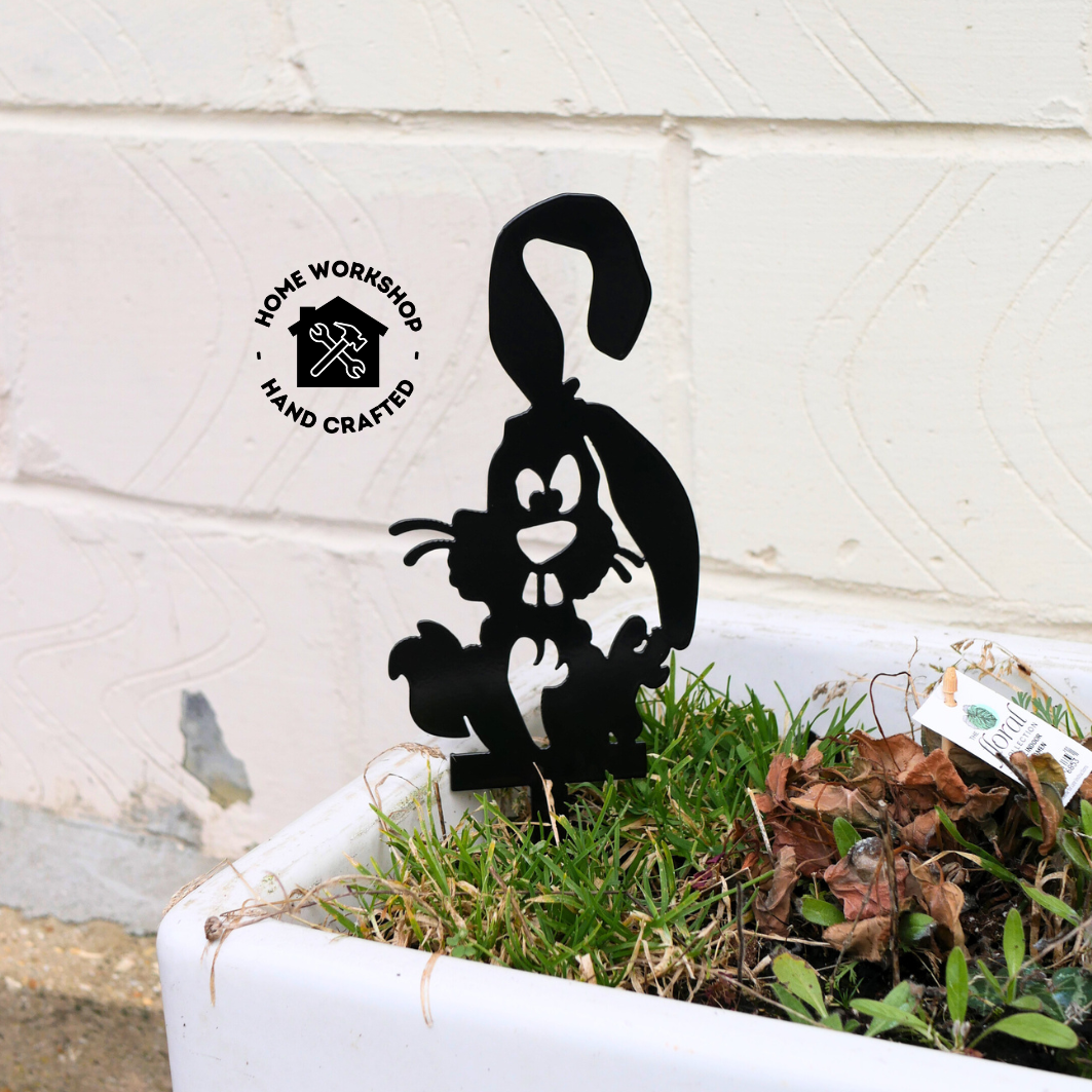 A metal black garden stake in the shape of a bunny rabbit.