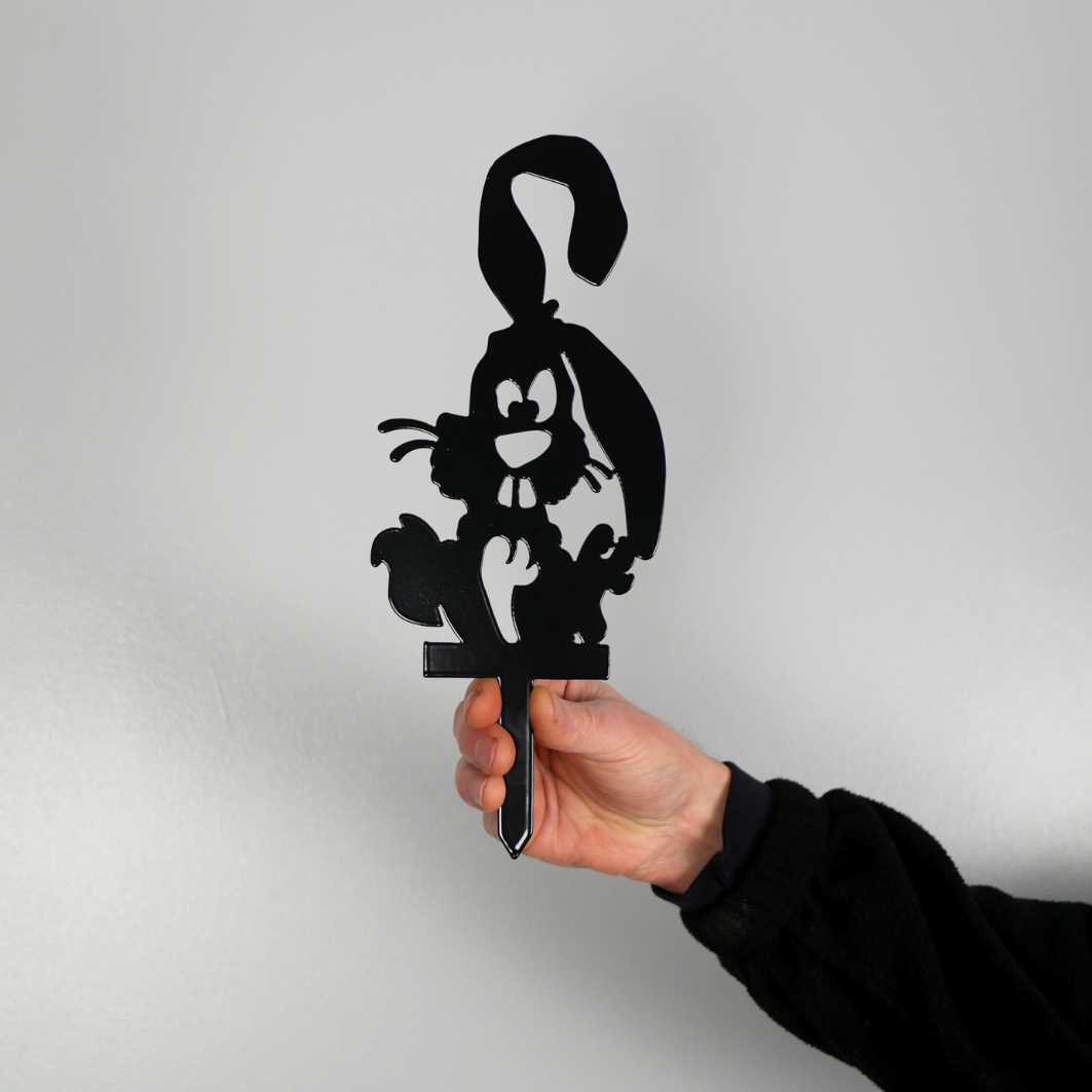 A man’s hand holding a metal black garden stake in the shape of a bunny rabbit.