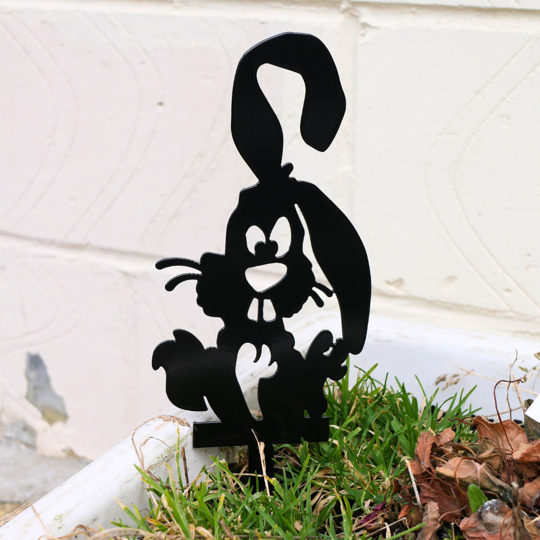 A close up of a metal black garden stake in the shape of a bunny rabbit.