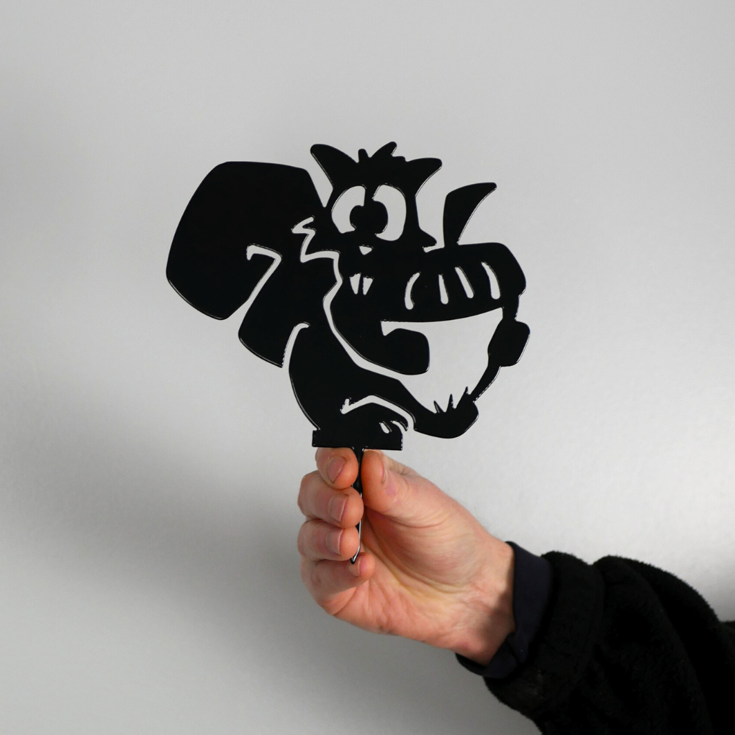 A man’s hand holding a metal black garden stake in the shape of squirrel holding an acorn.