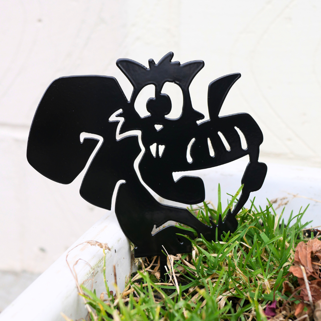 A close up of a metal black garden stake in the shape of squirrel holding an acorn.