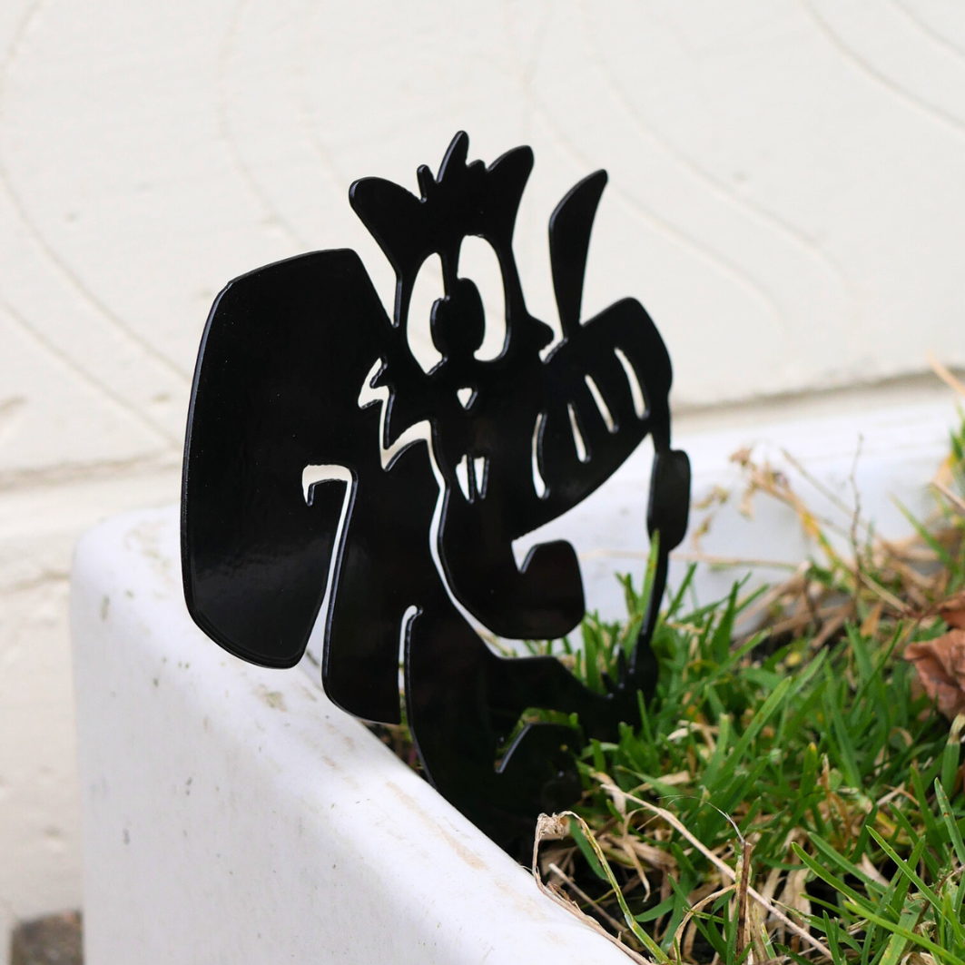 A side view angle of a metal black garden stake in the shape of squirrel holding an acorn.