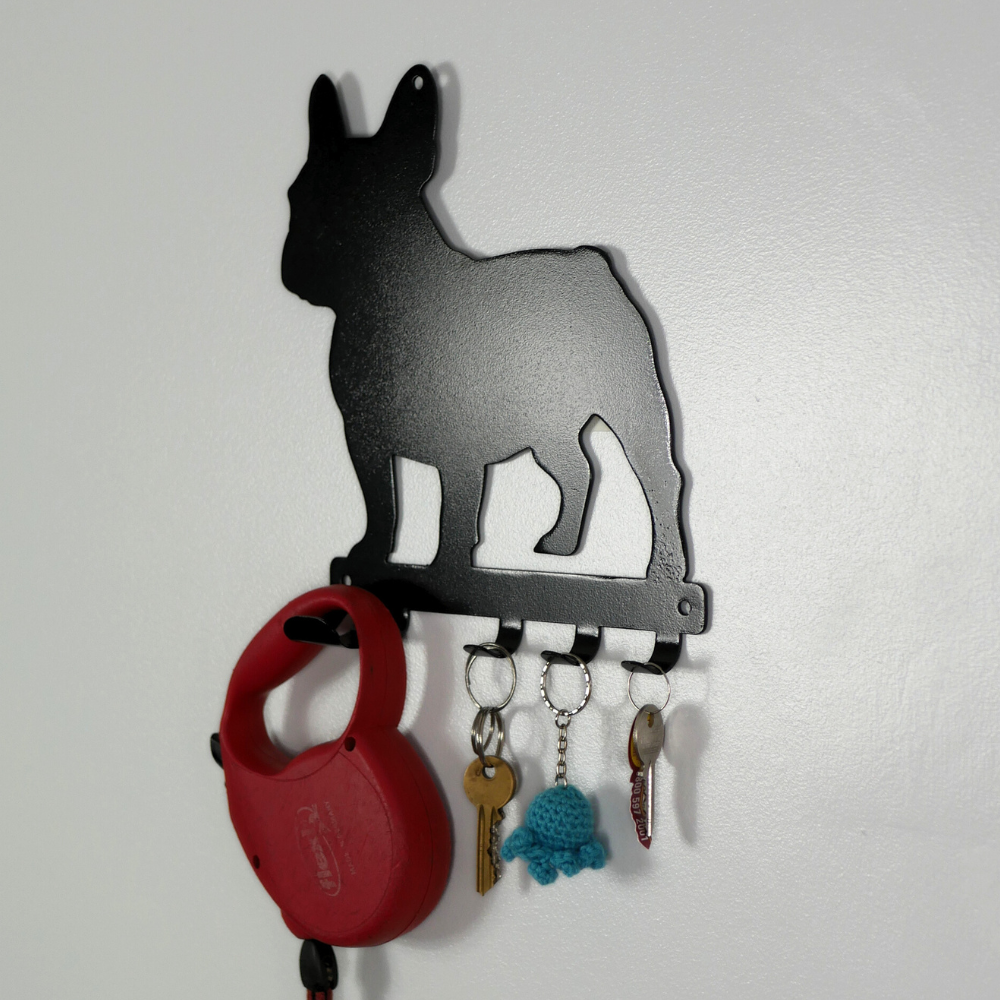 A side angle photo of a french bulldog shaped metal black dog lead and key rack. Hanging from the four hooks are a dog lead, keyring, and two keys.