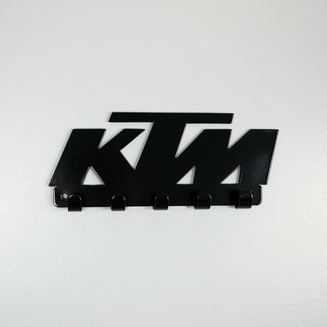 A black metal key rack in the shape of the KTM racing logo, it has 5 hooks.