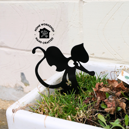 A metal black garden stake in the shape of a mouse or a rat.