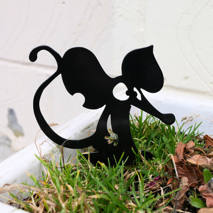A close up of a metal black garden stake in the shape of a mouse or a rat.