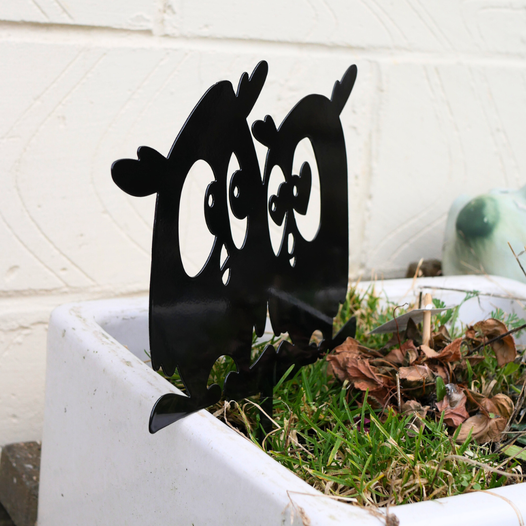 A side view angle of a metal black garden stake in the shape of two owls.
