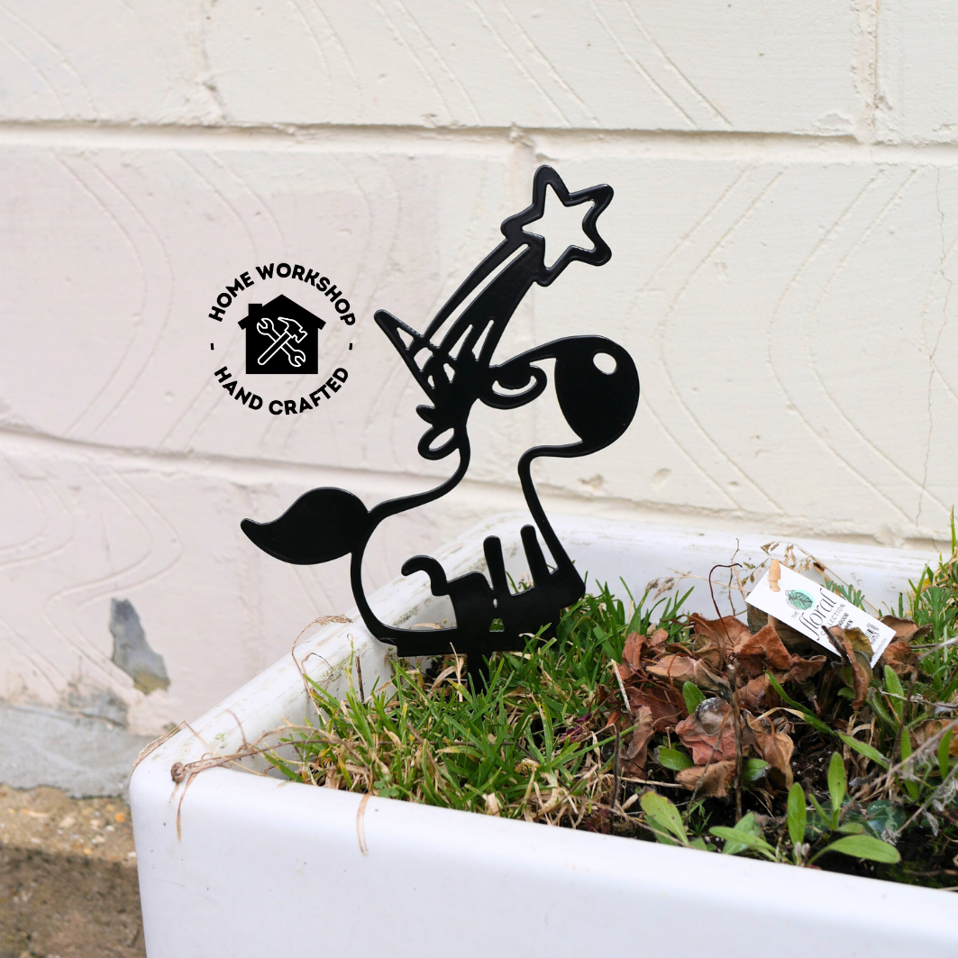 A black metal garden stake in the shape of a unicorn. It has a shooting star coming from its horn.